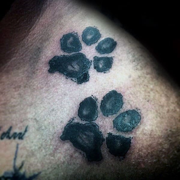 Tiny dog paws tattoo located on the wrist.