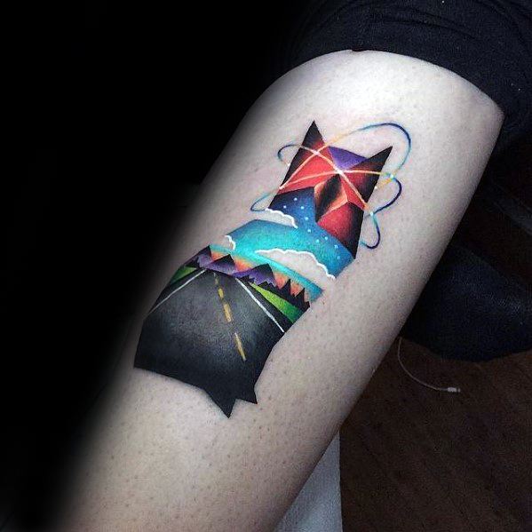 Colorful tattoo of a cat silhouette filled with a vibrant road trip scene, featuring mountains, clouds, and a cosmic sky above.