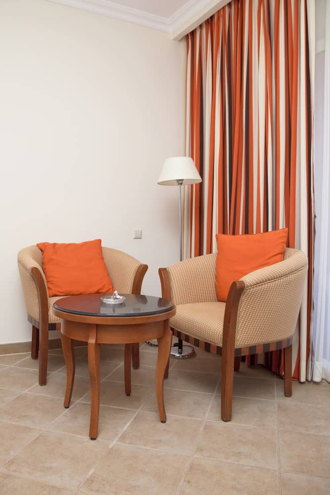 colorful drapes two chairs small table orange pillows