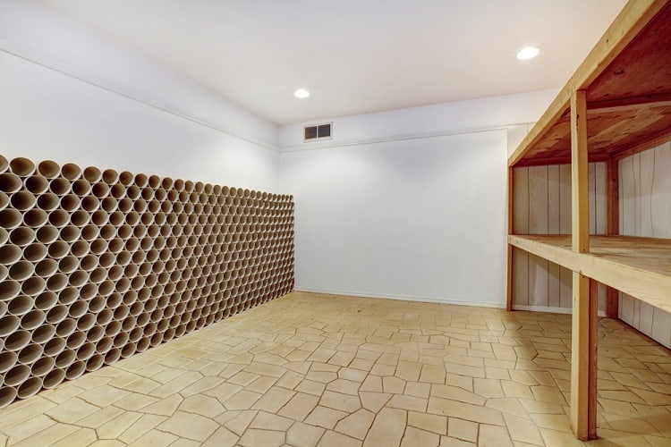 Minimalist wine cellar with wooden shelves and a wall of circular storage compartments.