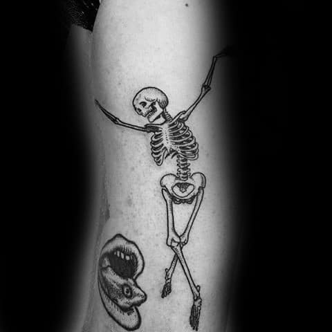 Dancing skeleton tattoo located on the inner forearm