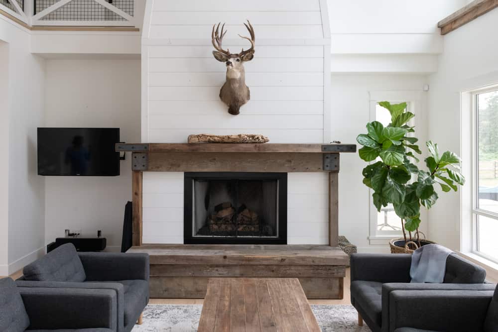 farmhouse living room shiplap wall wood fireplace gray sofas deer head