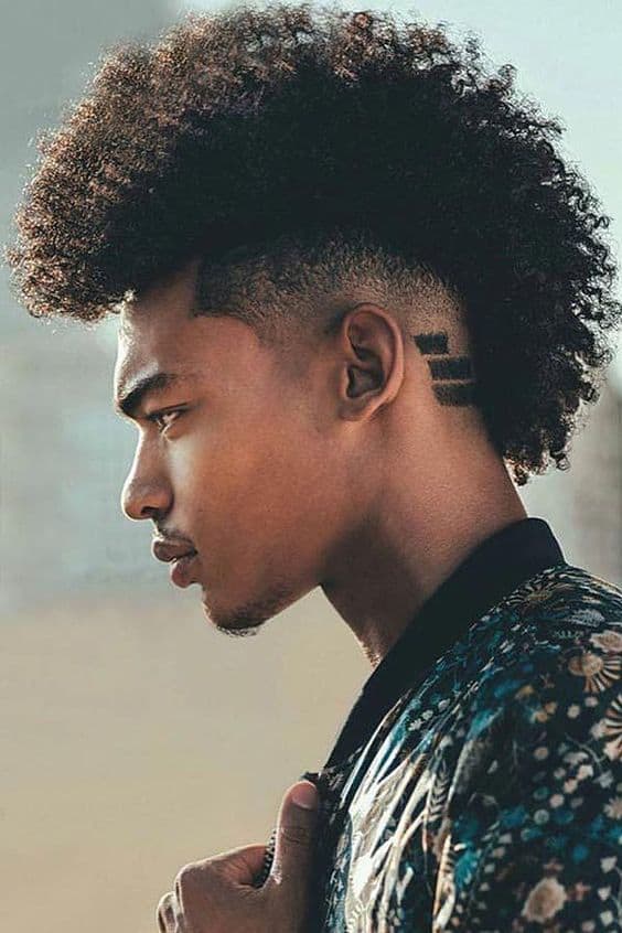 A complete faux frohawk men’s hairstyle with ‘fro hair on top and shaved sides. It is a great transitional hairstyle for men with braids