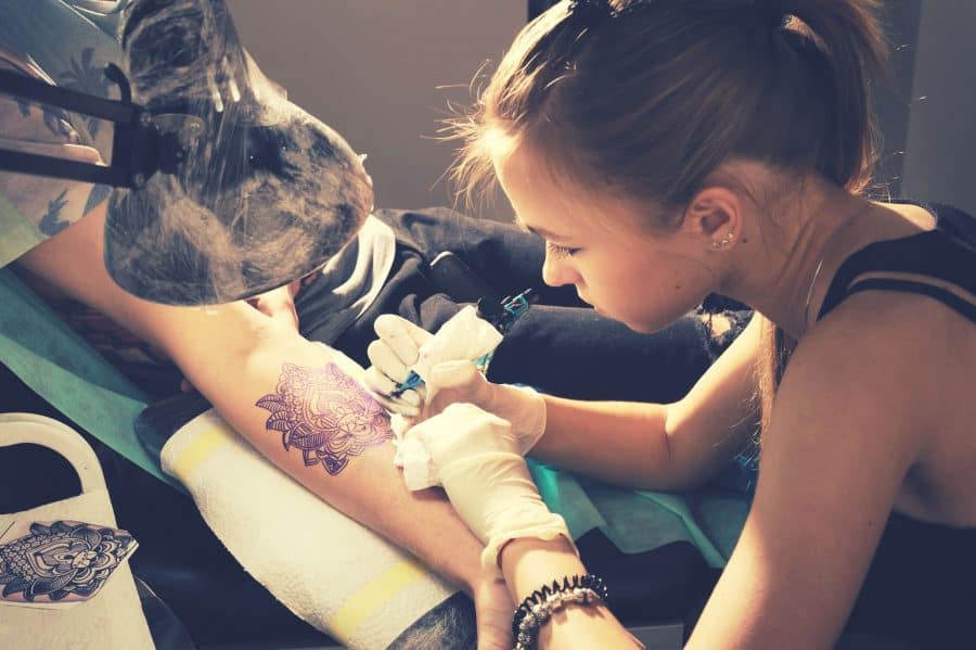 Female Artist Working Ink Tattooing Customer