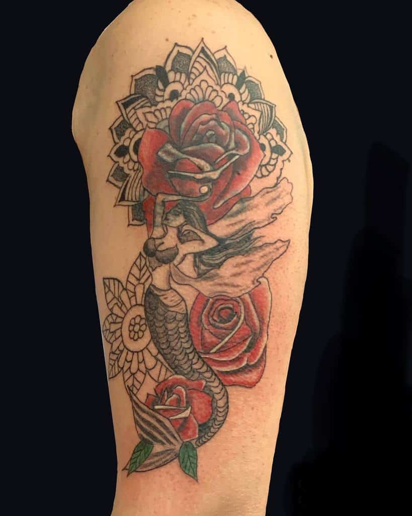 Ornate arm tattoo of a mermaid surrounded by red roses and intricate mandala-style floral patterns