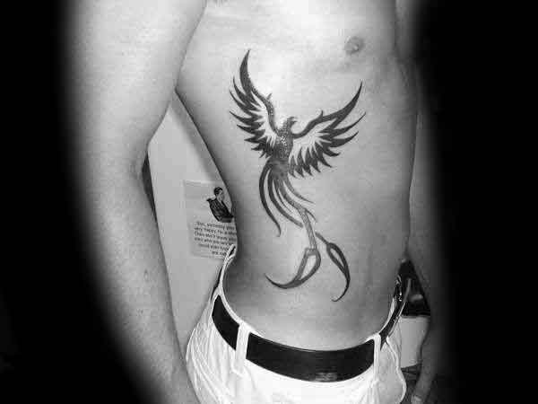 Flying Tribal Phoenix Male Black Ink Tattoo Design On Ribs