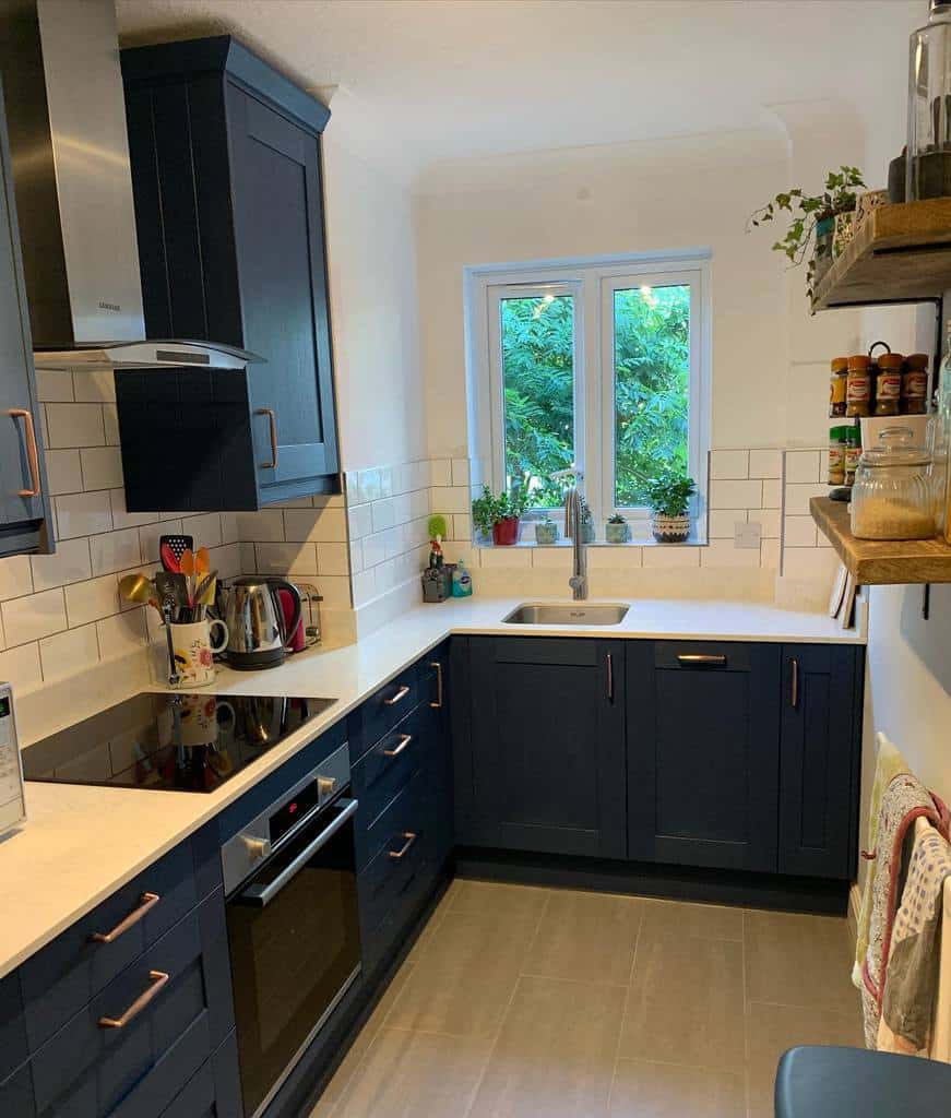 small kitchen with blue cabinets white countertop wood wall shelves 