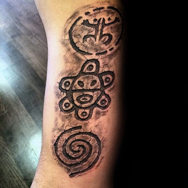 Gentleman With Carved Stone Taino Symbol Tattoos On Forearm