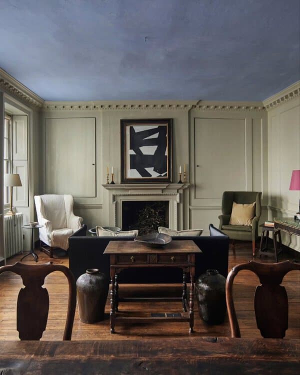 Georgian living room with a blue ceiling, neutral paneling, abstract artwork, and antique furnishings for a refined yet modern contrast.