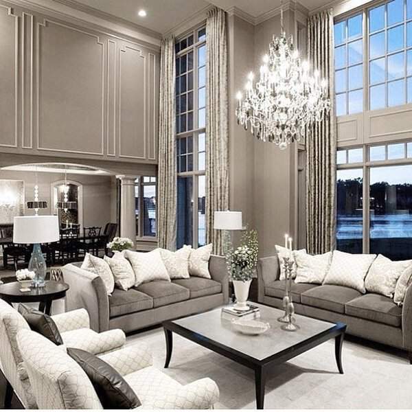 Elegant grey and white living room with high ceilings, crystal chandelier, and luxurious decor.