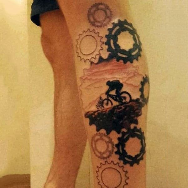 Guy With Gear And Rocky Ride On Bicycle Tattoo Legs