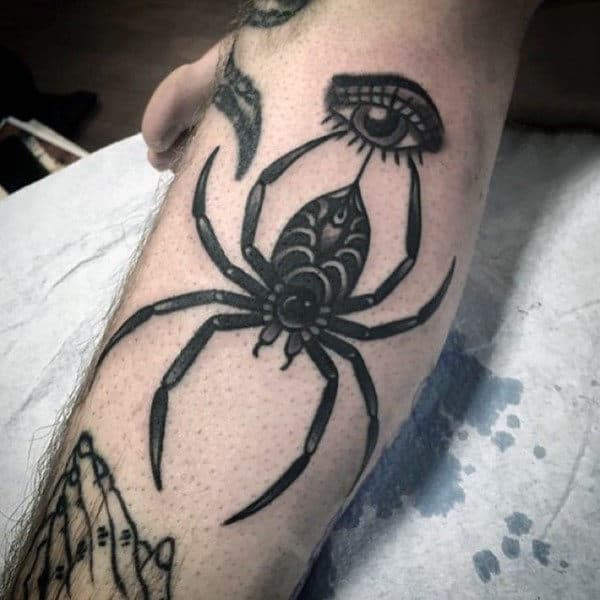 Guys Black Spider Holding An Eye Tattoo On Calf