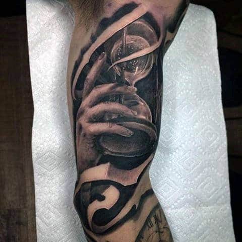 Hand Holding Sand Clock Hourglass On Arm Tattoo For Men
