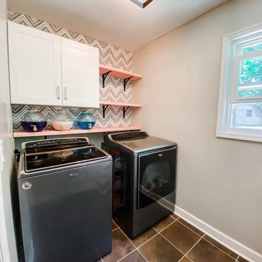 small laundry white wall cabinets pink shelves washer and dryer