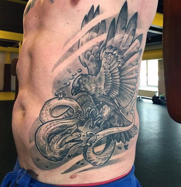 Hawk Fighting Cobra Snake Tattoo On Rib Cage Of Guy