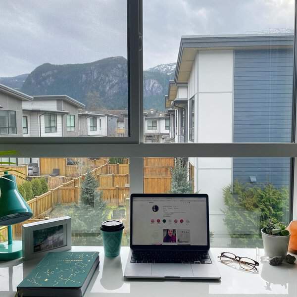 A well-organized desk with family photos, a planner, crystals, and a warm drink, creating a calming, focused workspace.
