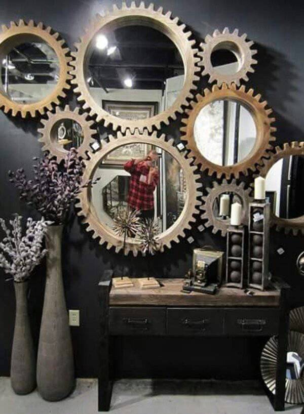 Gear-shaped mirrors on a dark wall create an industrial focal point, paired with rustic furniture, candles, and tall decorative vases.