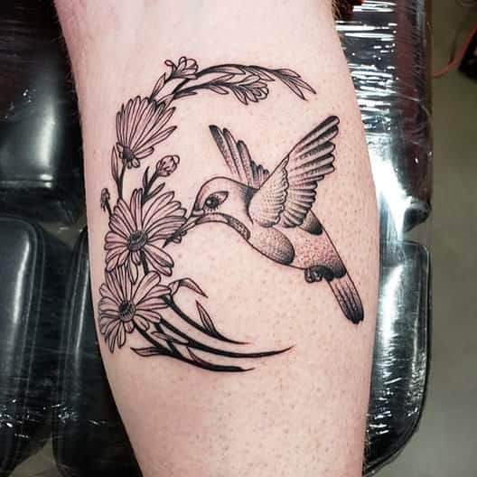 Calf tattoo black and grey stipple shading humming bird drinking from daisies
