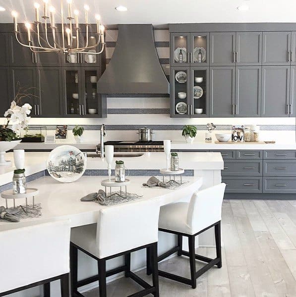 large modern kitchen with gray cabinets curved island with chairs and chandelier