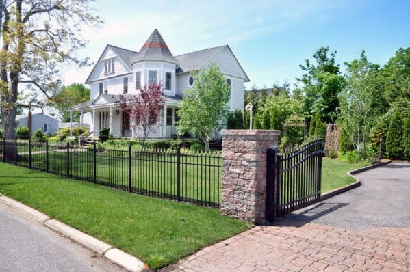 front yard fence wrought with stone pillar paved driveway
