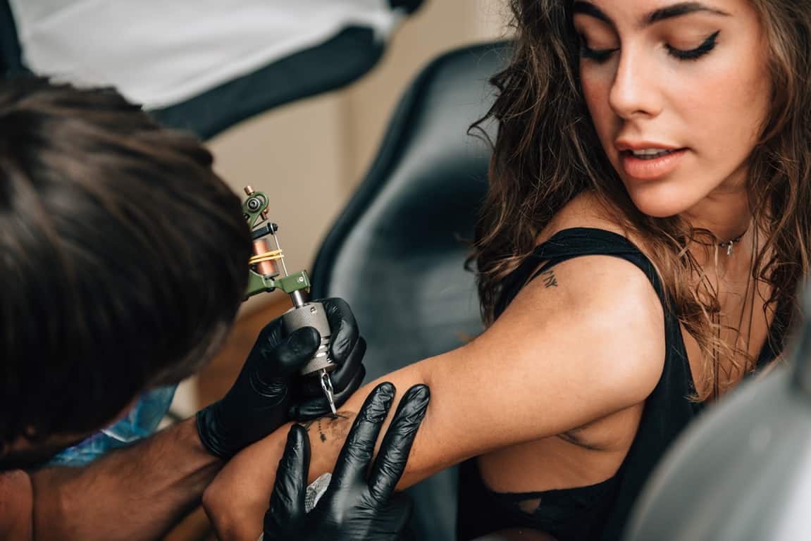 image of a woman getting tattoo