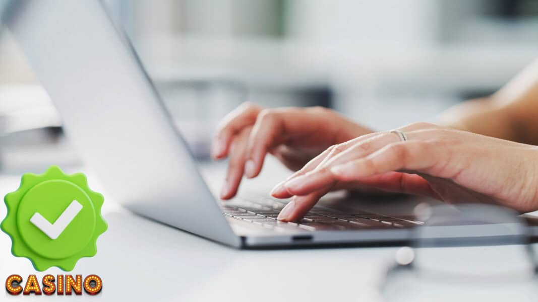Hands typing on a laptop keyboard, green checkmark badge with KYC and "CASINO" for online casino verification Poland