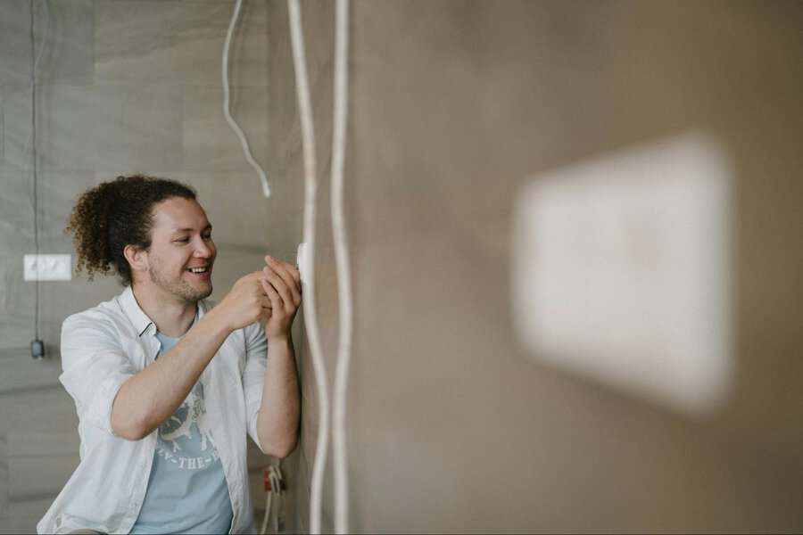 Person with curly hair smiling as they efficiently repair an electrical outlet, making sure the HVAC system works properly
