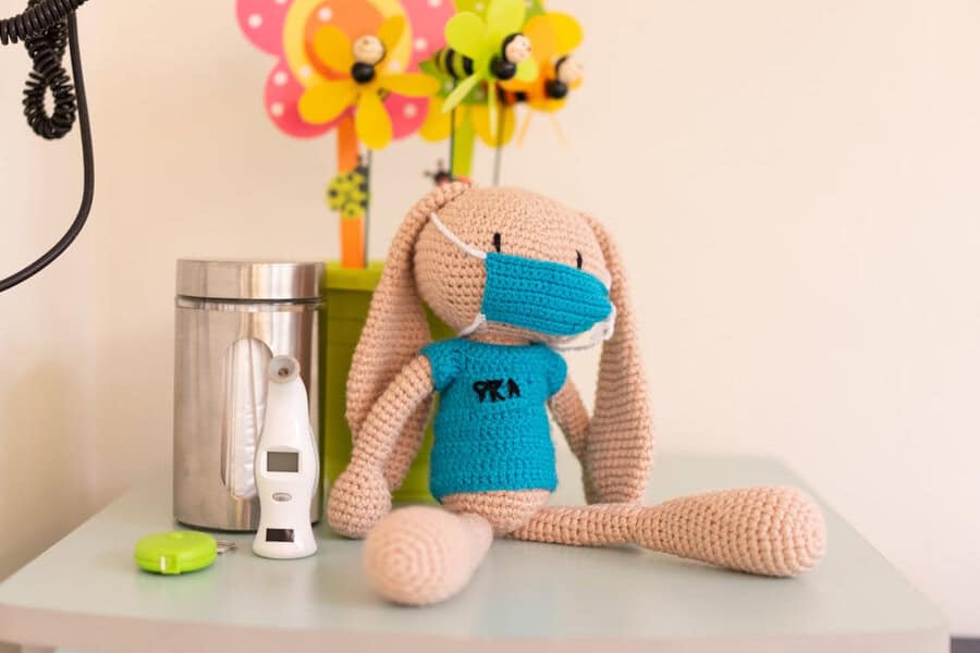 A crocheted bunny wearing a blue shirt and face mask sits on a table, suggesting research in cerebral palsy with stem cell therapy