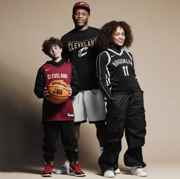 Three people striking basketball poses—a child holding a ball, an adult in Cleveland apparel, and another wearing Brooklyn streetwear
