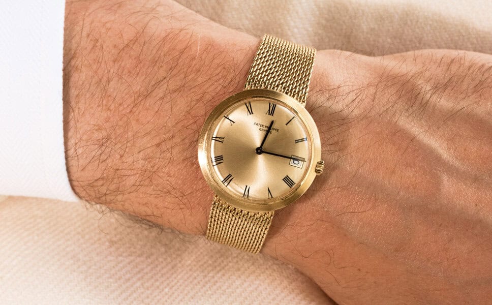 A gold wristwatch with a mesh band and Roman numerals adds authenticity to any vintage watch collection