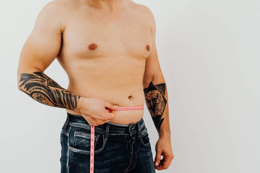 Man without a shirt measuring his waist