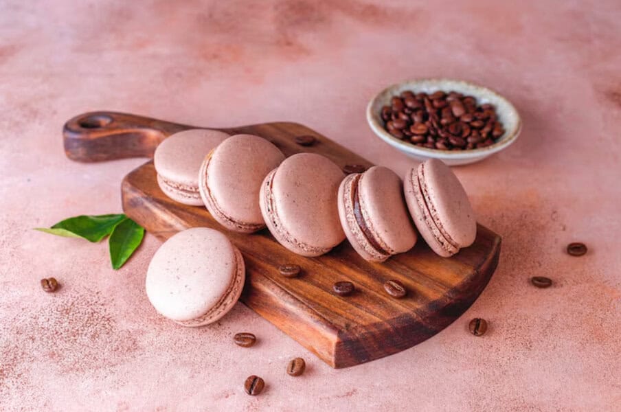 Coffee macarons on a wooden board with coffee beans—an elegant choice for wedding desserts or special event treats