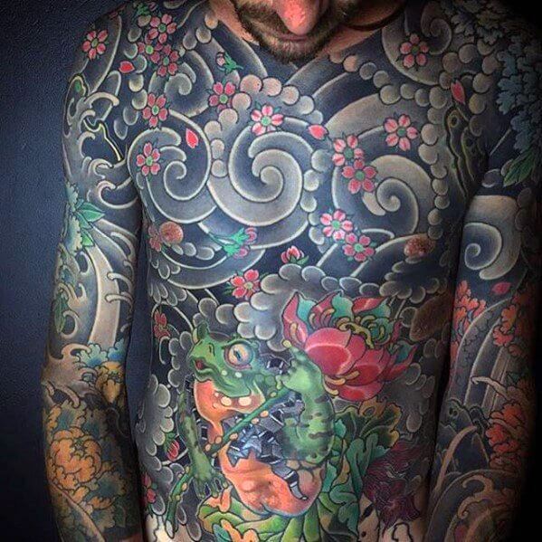 Japanese full-chest and arm tattoo featuring a vibrant frog, swirling clouds, cherry blossoms, and intricate floral elements