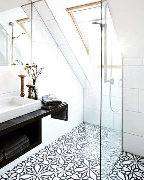 Bright bathroom with slanted skylight, patterned floor tiles, and glass walk-in shower.