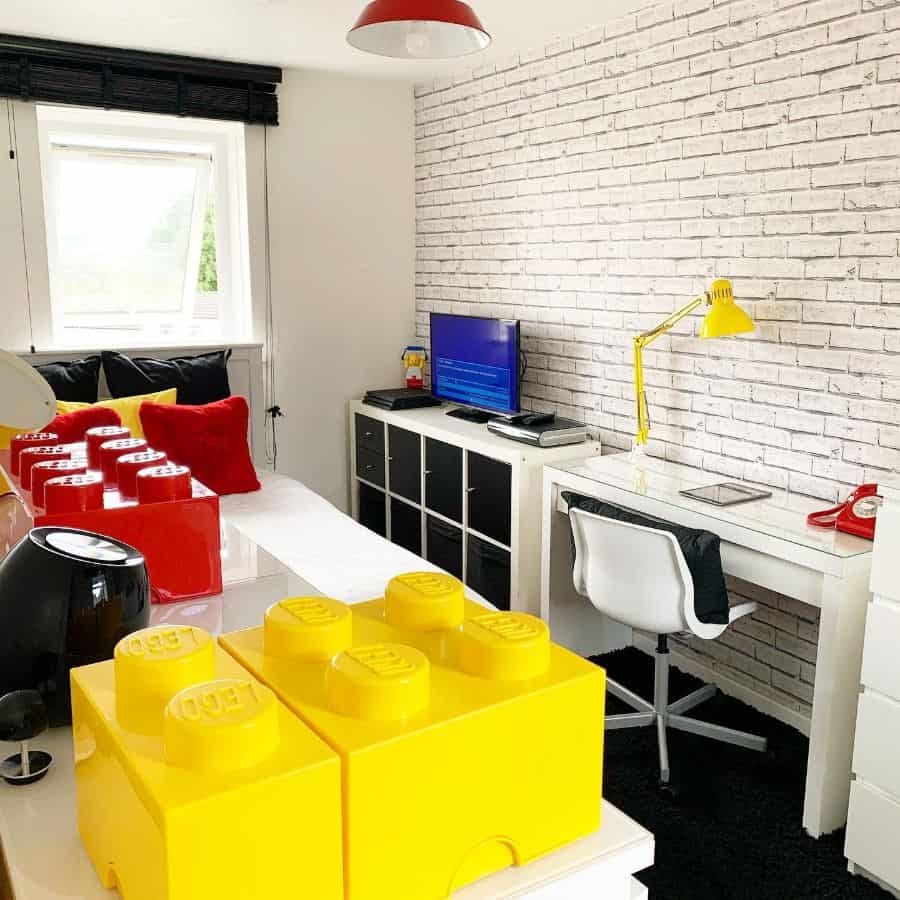 Kids' room with large LEGO storage blocks, white desk, and brick wallpaper.