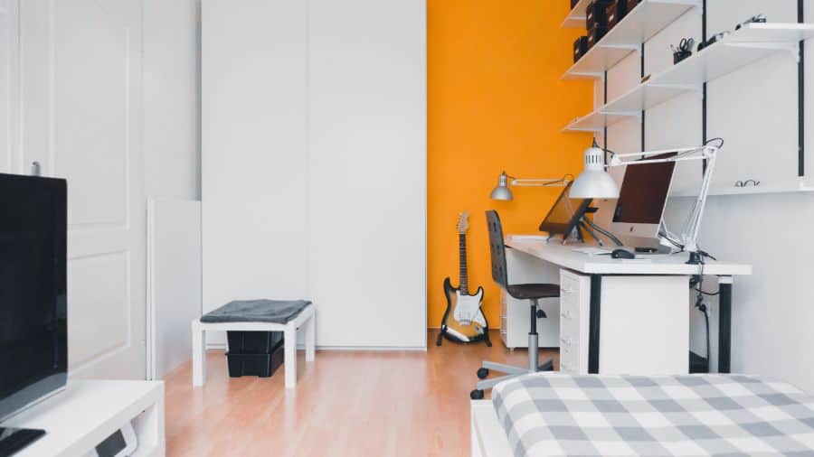 small bedroom orange feature wall computer desk guitar 