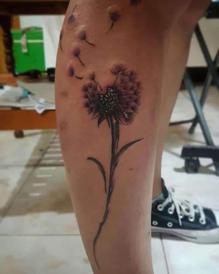 leg flying dandelion tattoo