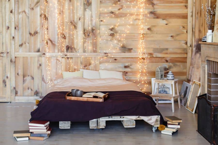 platform pallet bed in rustic bedroom with fairy lights 