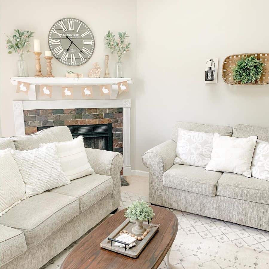 neutral color farmhouse living room with gray sofas and stone fireplace 