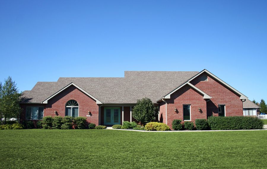red brick ranch-style home with manicured lawn