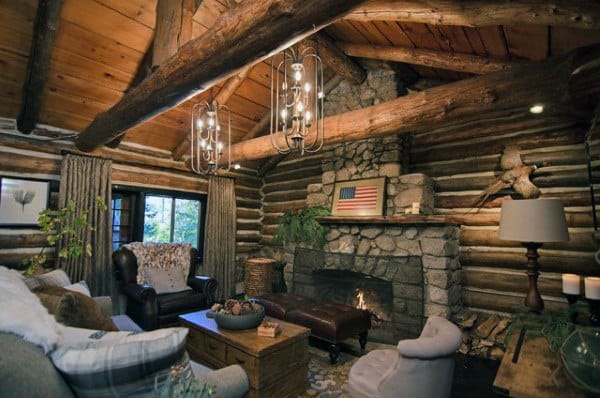 cozy log cabin living room stone fireplace brown leather ottoman