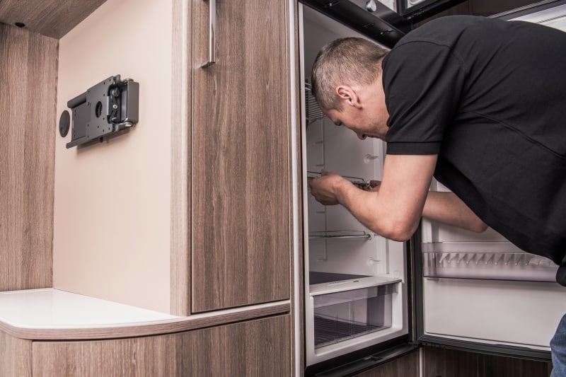 man-install-fridge-surviving-van-life