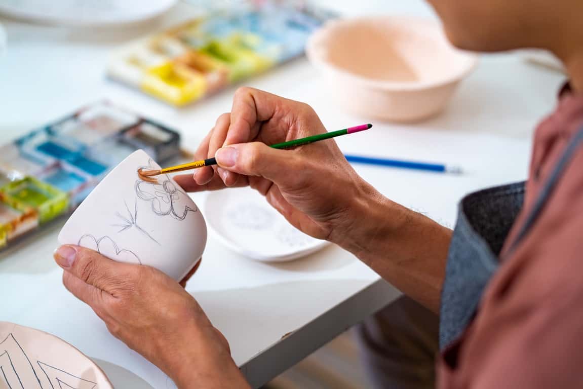 man painting self-made pottery mug at home