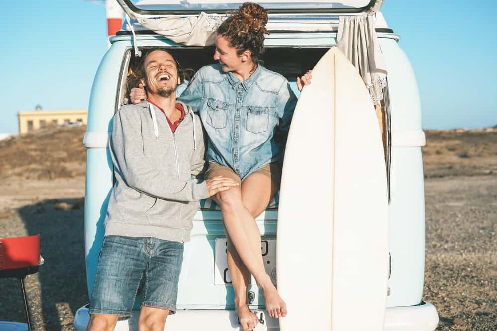 A man dressed in shorts and a hoodie sweatshirt laughing with a woman