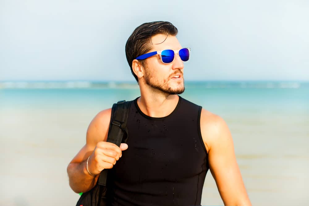 A man carrying a backpack and wearing blue mirrored sunglasses