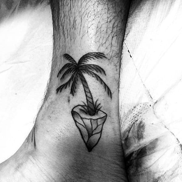 Man With Black Palm Tree Tattoo On Ankles