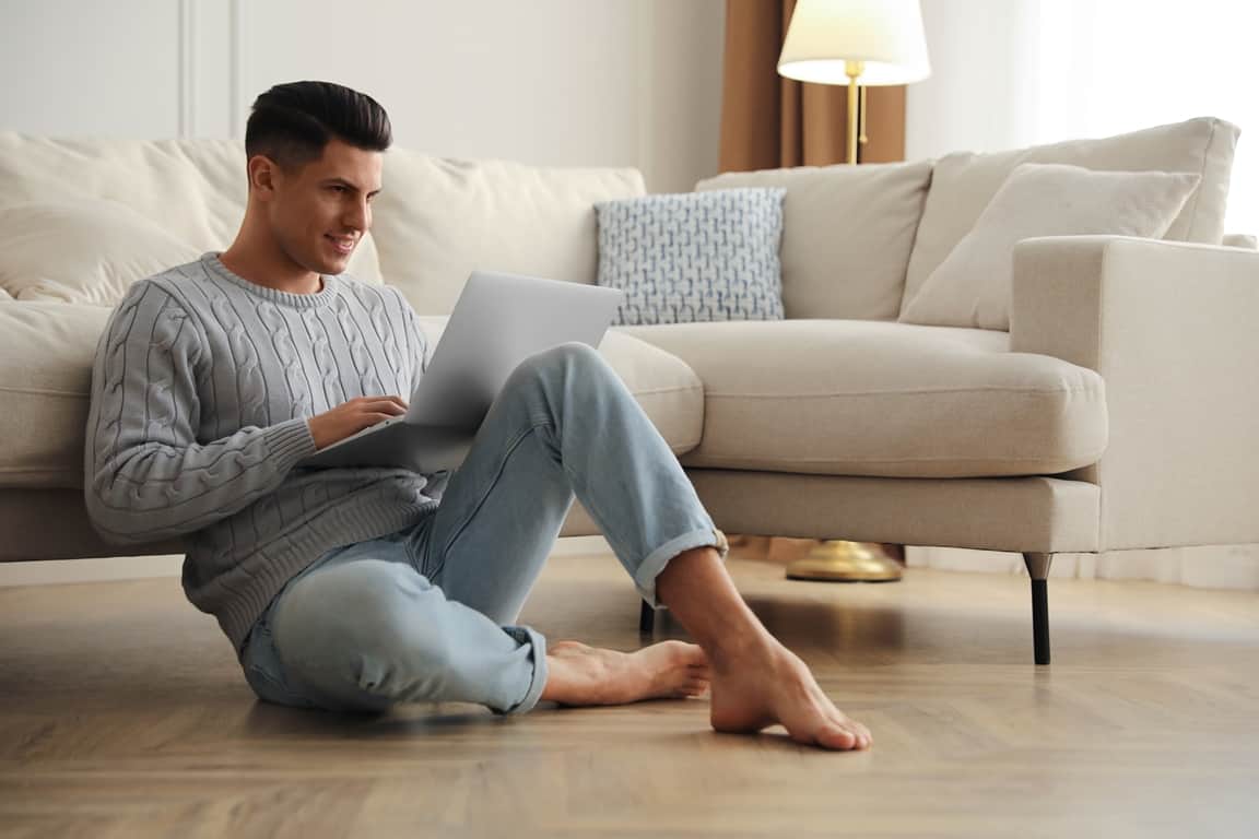 man with laptop sitting on floor in living room