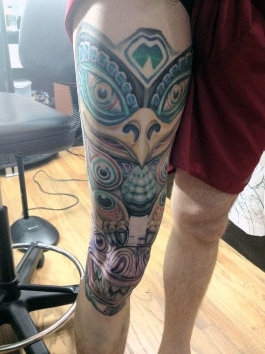 Man With Large Grinning Totem Pole Thigh Piece Tattoo