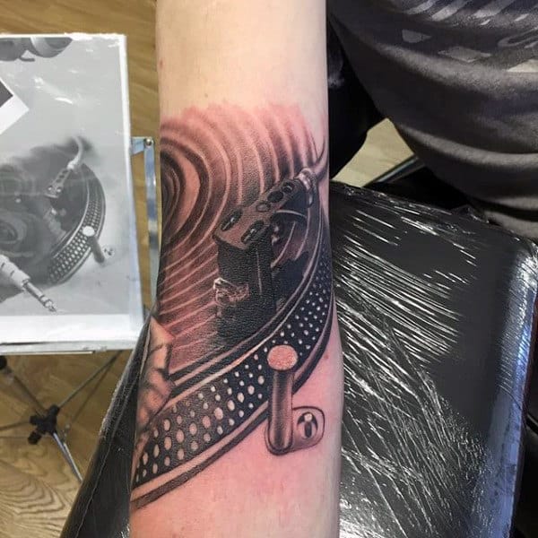 Man With Spiral And Dotted Musical Tattoo On Forearms