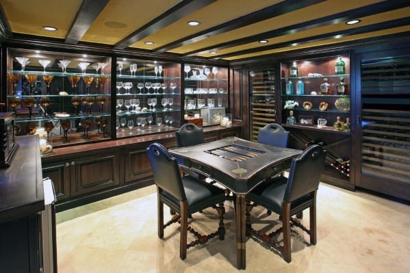 Elegant bar room with dark wood cabinetry, glassware displays, and a central game table for drinks.